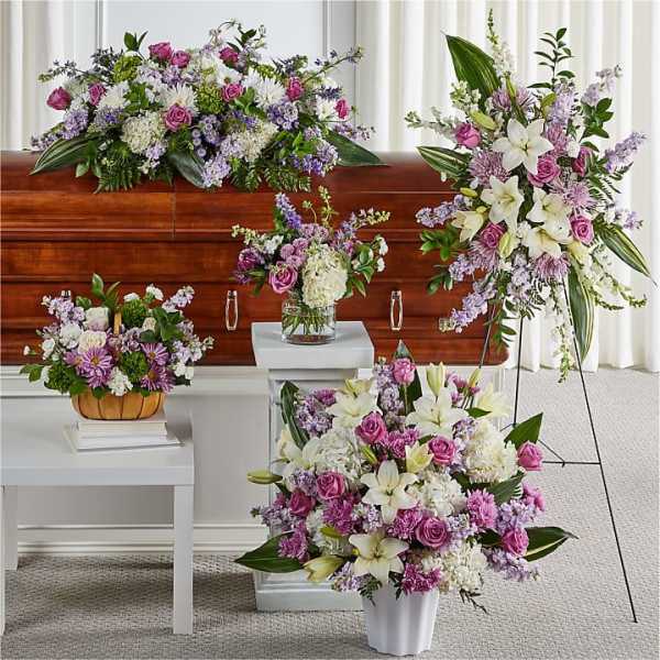 Funeral floral set with pink, white, and lavender arrangements around a casket