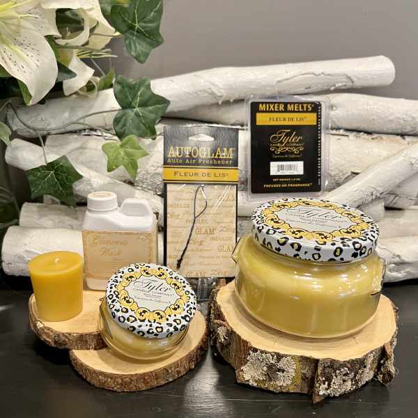 Candles and fragrance products arranged on wood slices with faux flowers in the background