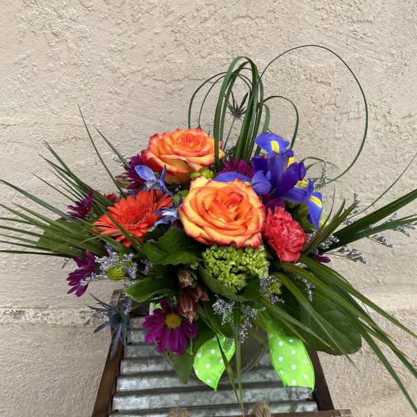 Colorful bouquet with orange roses, purple irises, and a green ribbon in a vase