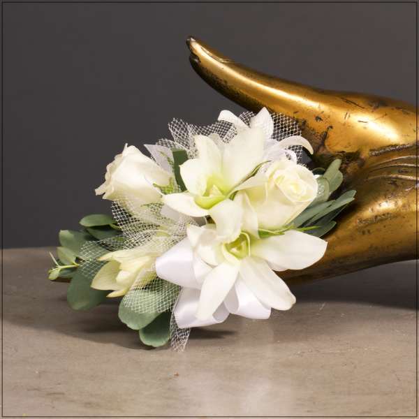 White floral corsage with roses and orchids beside a gold horn
