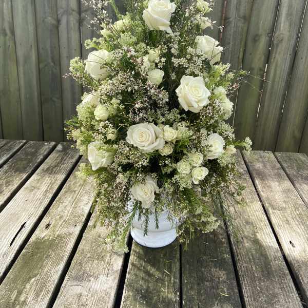Tall white rose arrangement in a white vase
