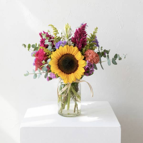 Sunflower bouquet in a glass jar vase with colorful mixed flowers