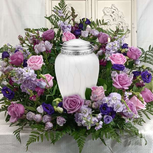 Purple and pink rose funeral wreath with a white urn centerpiece