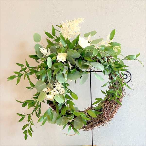 Green wreath with white flowers on a metal stand