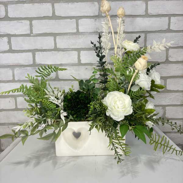 White floral arrangement in a rectangular vase with mixed greenery