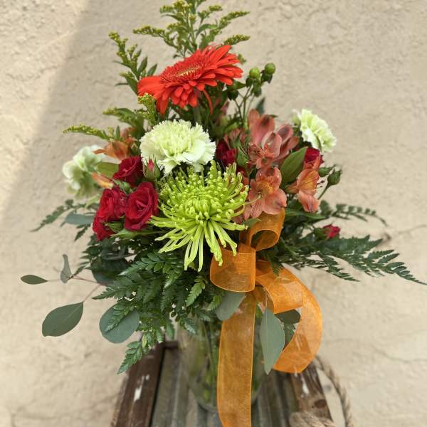 Mixed bouquet in a glass vase with red, green, and peach flowers