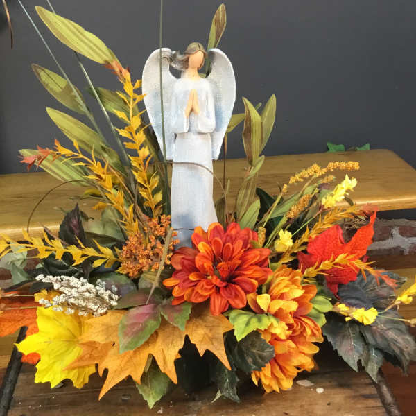 Autumn floral arrangement with an angel figurine and orange-yellow flowers