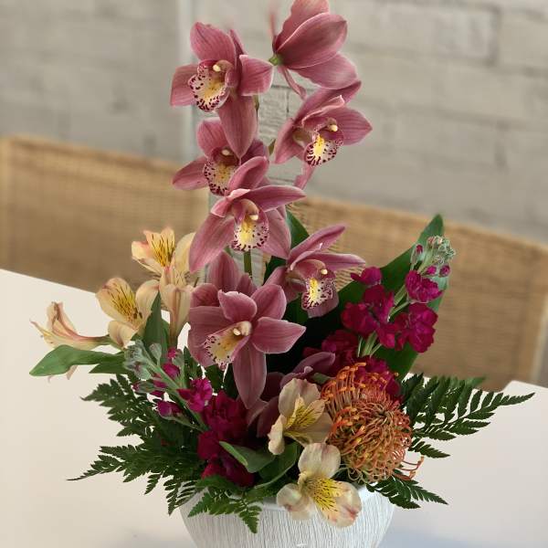 Pink orchid arrangement in a white textured vase