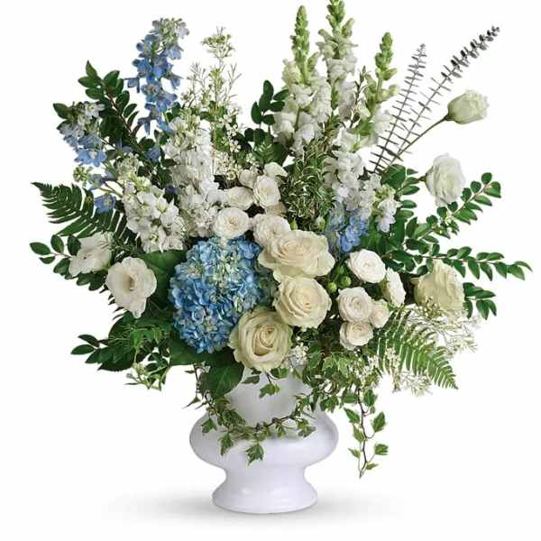 White and blue floral arrangement in a white pedestal vase