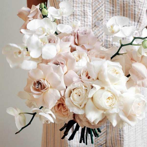 Bouquet of pale roses and white orchids held in hand