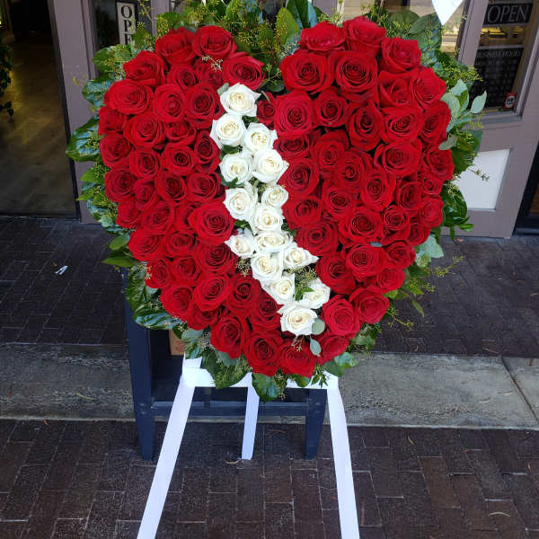 Heart-shaped red and white rose arrangement on an easel with white ribbon