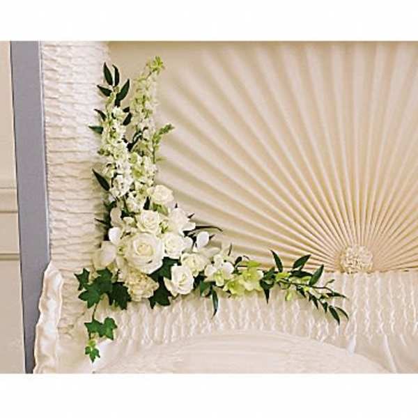 White floral arrangement with roses and orchids on a draped display
