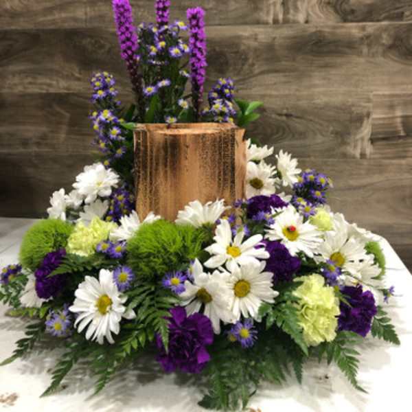 White daisies and purple flowers arranged around a copper vase
