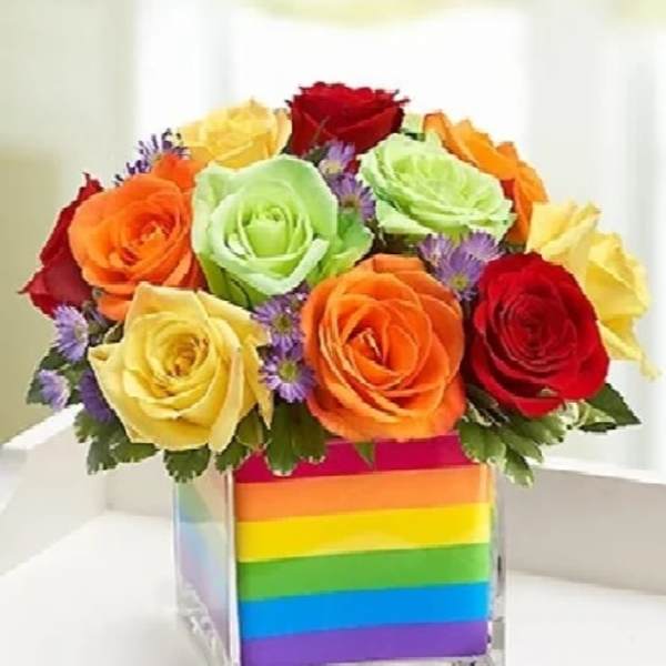 Rainbow rose bouquet in a clear cube vase with striped wrap