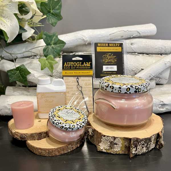 Pink candles and fragrance products on wood slices with faux ivy