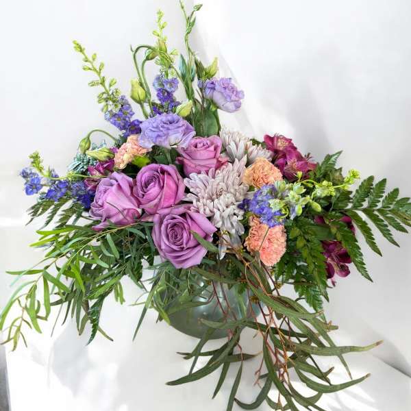 Lavender roses and mixed blooms in a low green vase