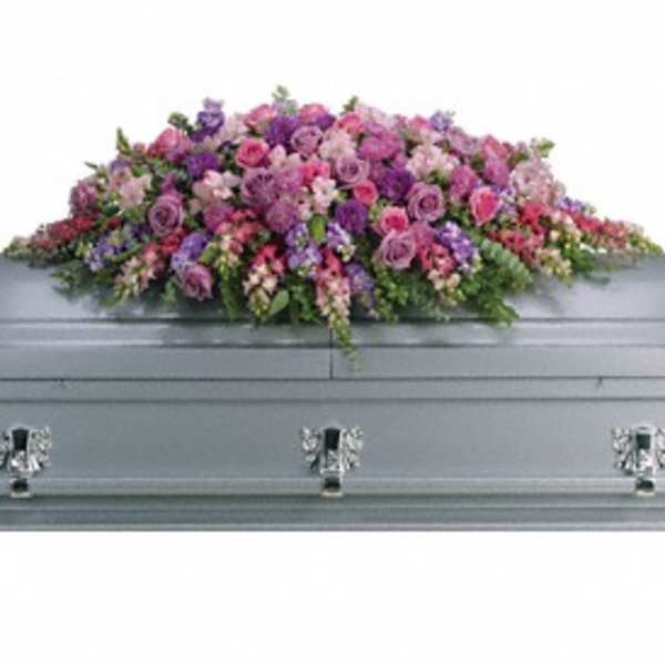 Pink and purple floral casket spray on a gray casket