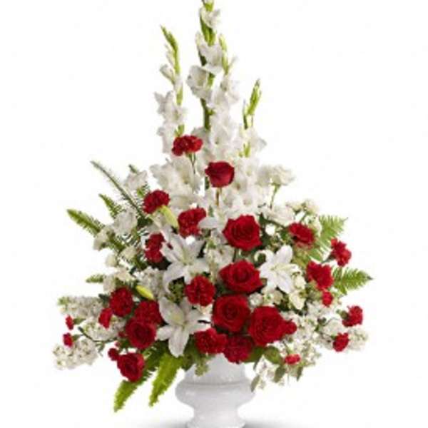 Tall red and white floral arrangement in a white urn