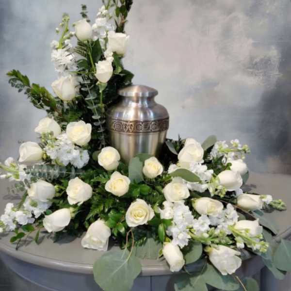 White rose floral arrangement around a silver urn