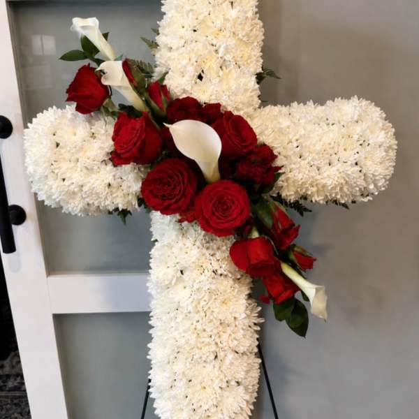 Cross-shaped floral tribute with white chrysanthemums, red roses, and white calla lilies