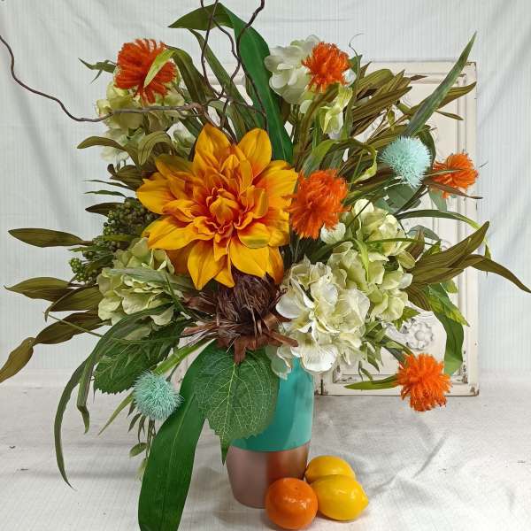 Orange and white floral arrangement in a turquoise vase with decorative branches