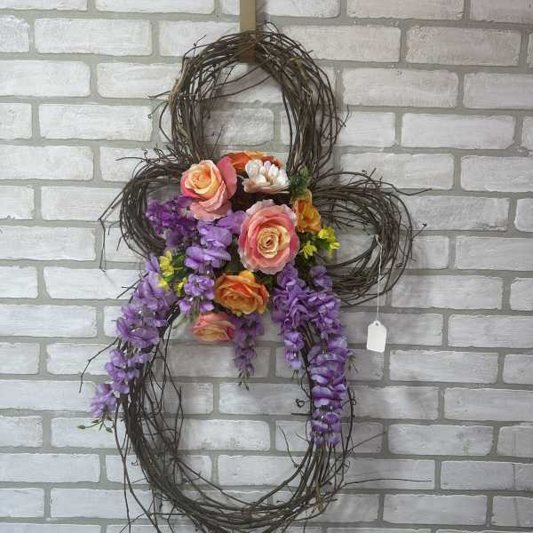 Floral wreath with purple hanging blooms and peach roses on a twig frame