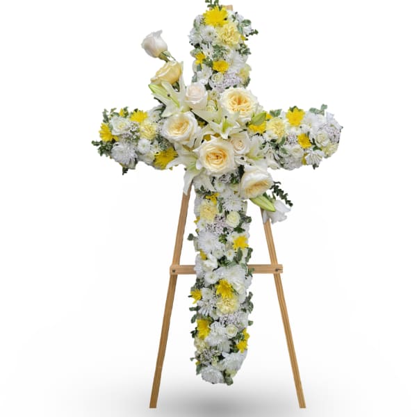 Cross-shaped floral tribute on a wooden easel with white and yellow flowers