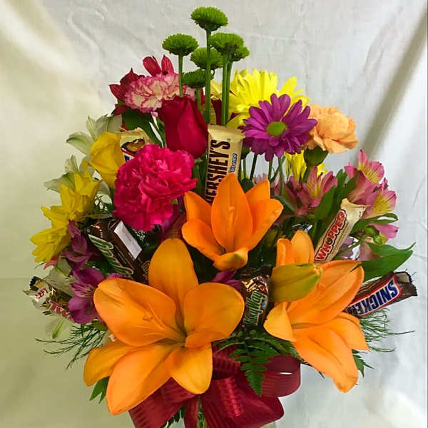 Bright mixed bouquet with orange lilies and assorted flowers in a glass vase
