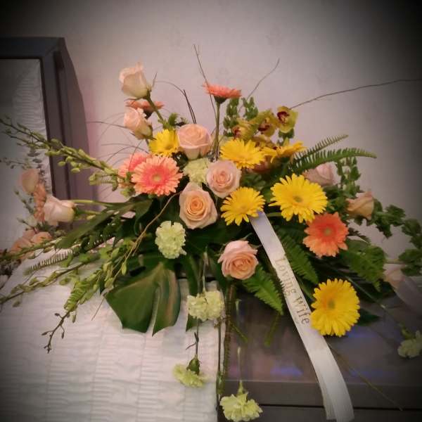 Mixed floral spray with roses and daisies on a casket
