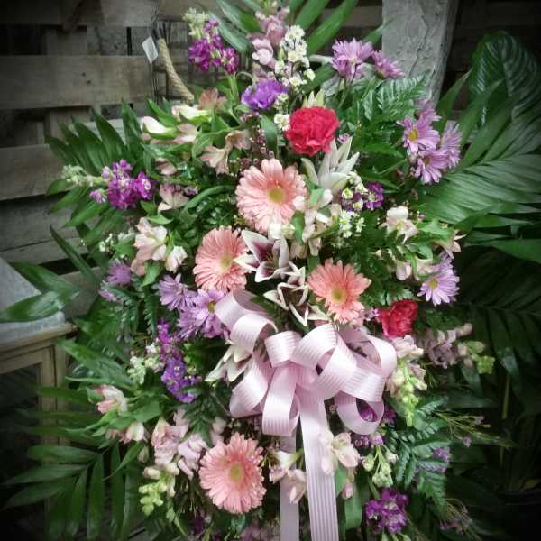 Large pink and purple floral standing spray with a ribbon bow