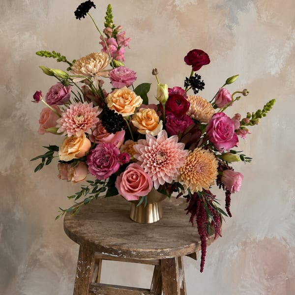 Mixed pink and peach floral arrangement in a gold vase