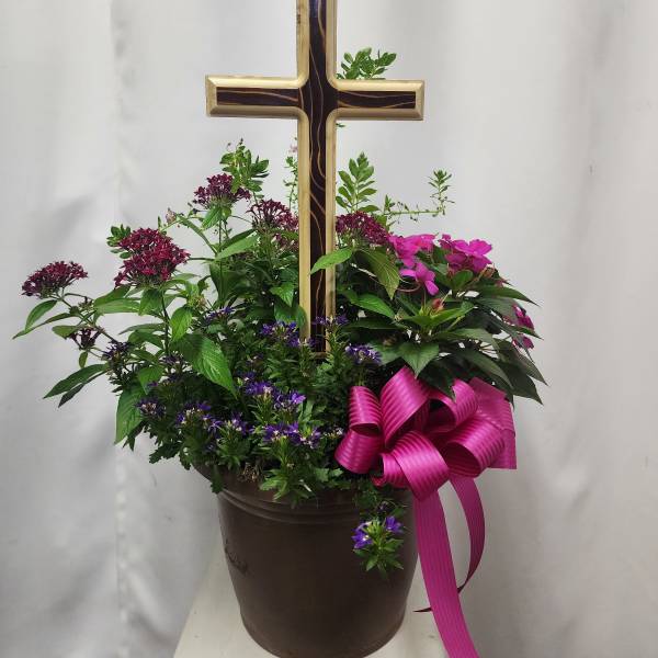 Potted floral arrangement with a wooden cross and pink ribbon