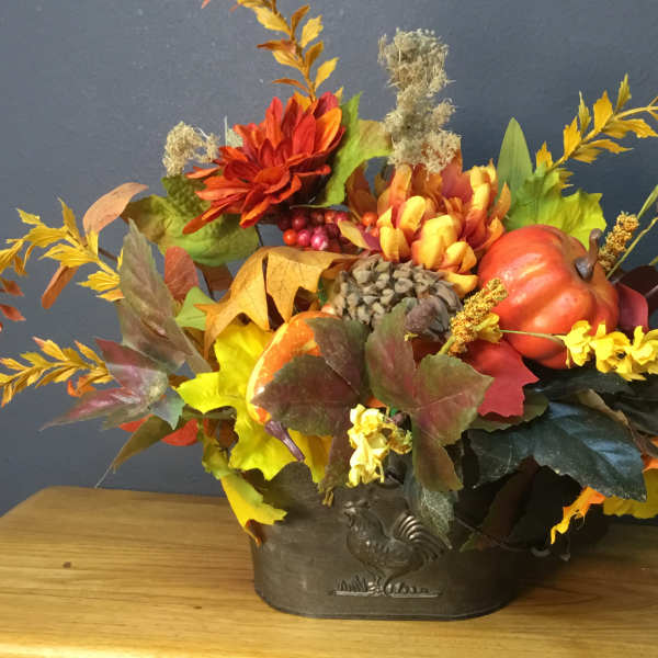 Autumn floral arrangement with pumpkins in a metal container