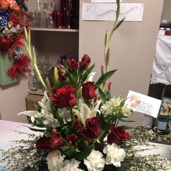Tall red and white floral arrangement with roses, lilies, and carnations