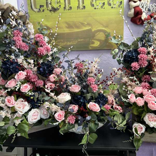 Three large floral arrangements with pink and white roses and dark blue blooms.