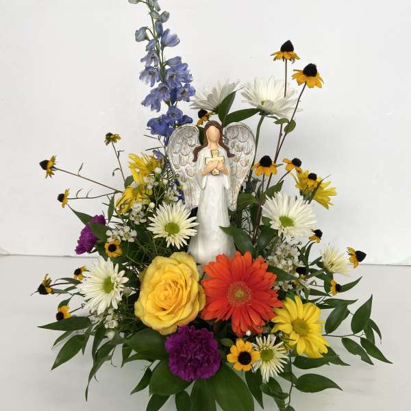 Mixed flower arrangement with an angel figurine in the center