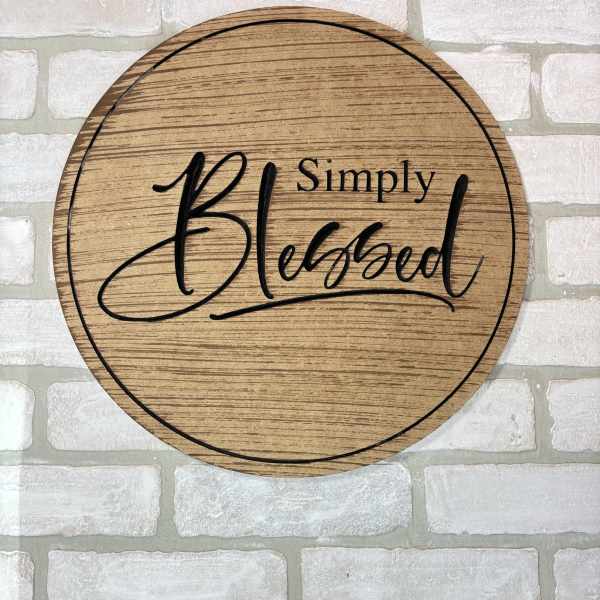 Round wooden sign reading "Simply Blessed" on a white brick wall