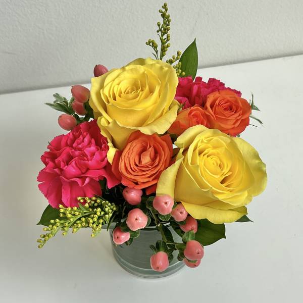 Bouquet of yellow, orange, and pink flowers in a glass vase