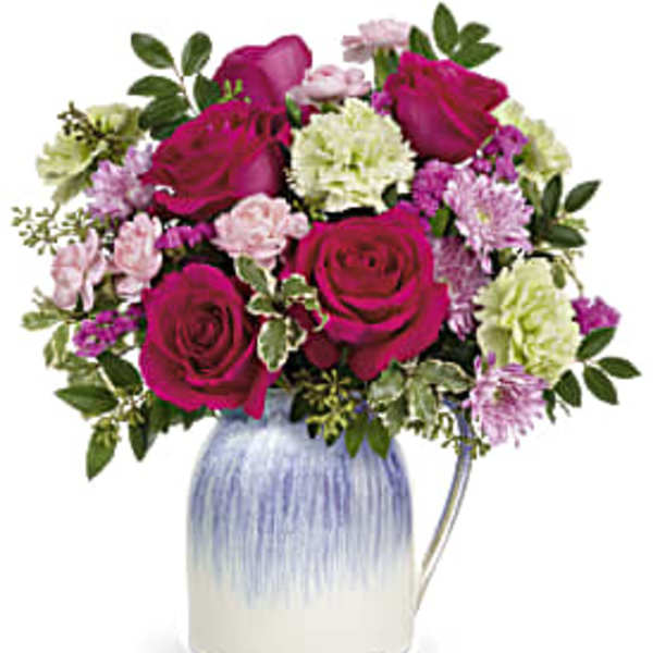 Bouquet of magenta roses and pastel carnations in a blue-and-white vase