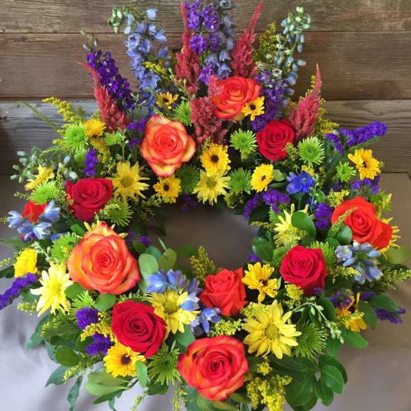 Colorful floral wreath with roses, daisies, and purple spikes