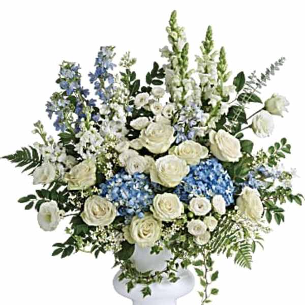 White and blue floral arrangement in a white pedestal vase