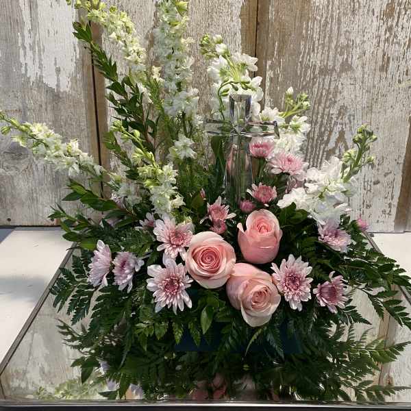Pink roses and white flowers arranged around a glass cross