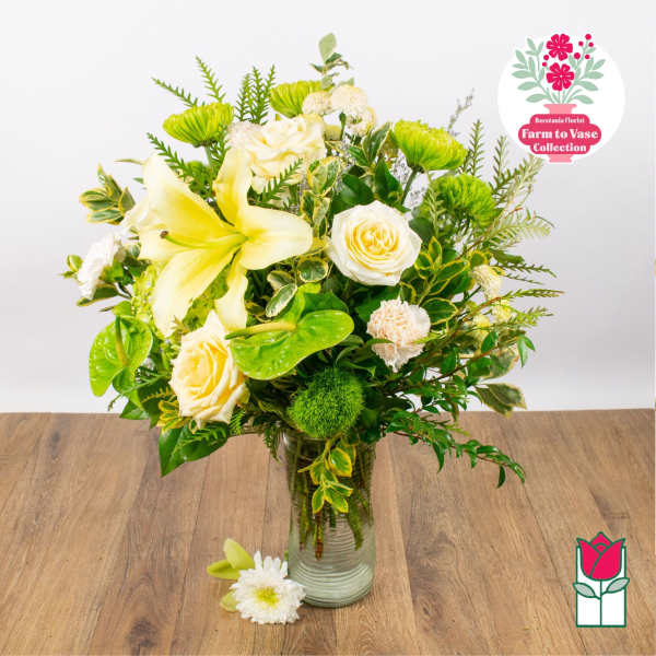 Yellow lilies and white roses arranged in a glass vase