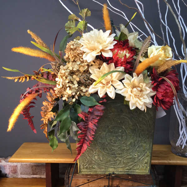 Autumn floral arrangement with cream and red blooms in a green container