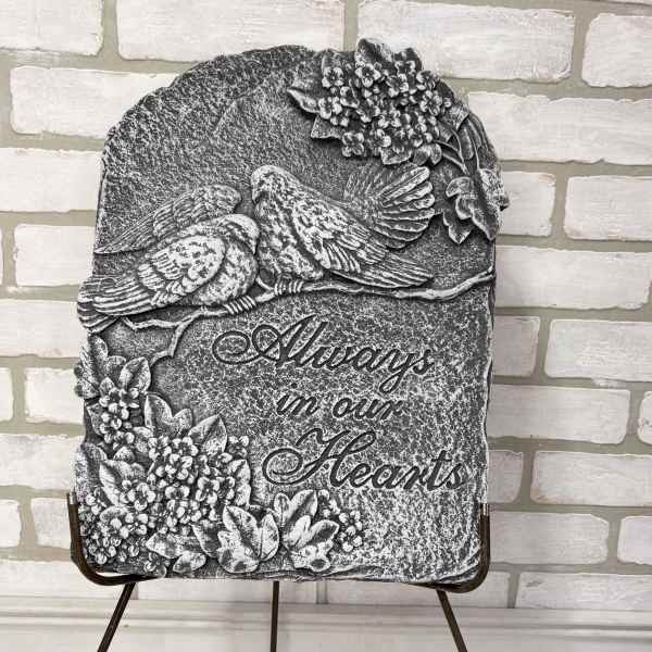 Stone memorial plaque with two birds and floral relief, reading "Always in our Hearts"