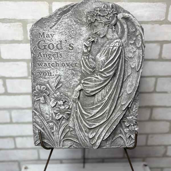 Gray memorial plaque with an angel and flowers on a stand