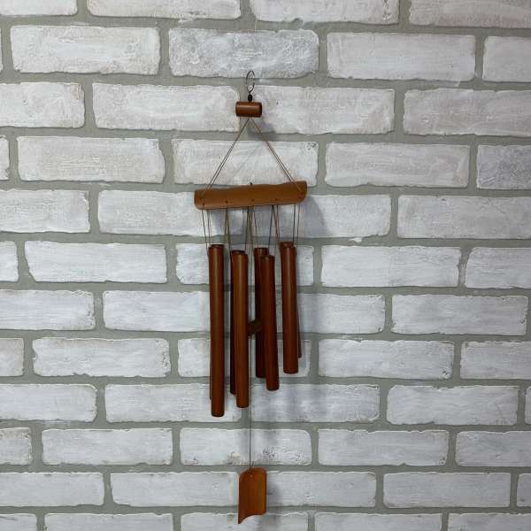 Wooden wind chime hanging on a white brick wall