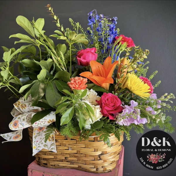 Mixed bouquet in a woven basket with bright roses and lilies