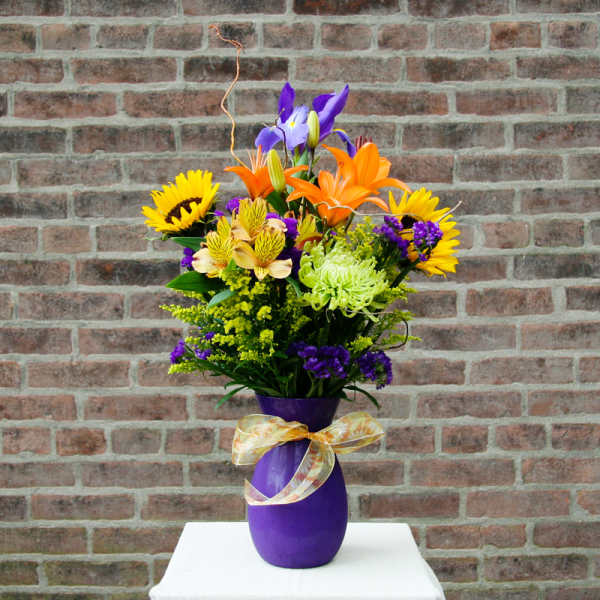 Colorful bouquet in a purple vase with a ribbon bow