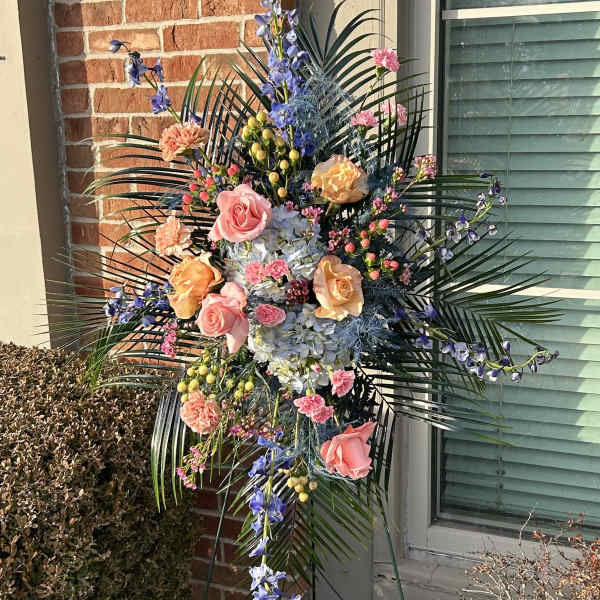 Tall standing floral spray with pink and peach roses and blue flowers